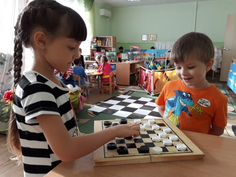 девочка учит играть в шашки